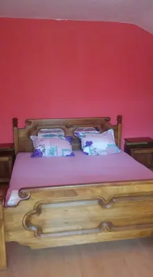 a bedroom with a wooden bed with a red wall at Къща за гости Пеневи in Sofia