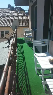 two white chairs on a balcony with green grass at Къща за гости Пеневи in Sofia