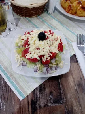 a plate of food with a salad on a table at Къща за гости Романс in Yagodina