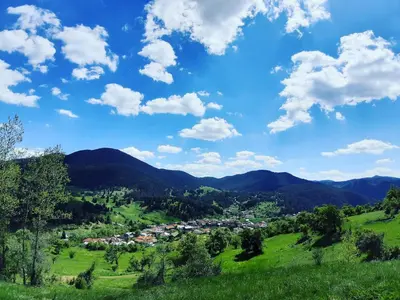 a village in the mountains under a blue sky with clouds at Къща за гости Романс in Yagodina