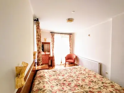 a bedroom with a bed and a desk and a window at Вила Цветелина, Комплекс Александриa in Dobrinishte