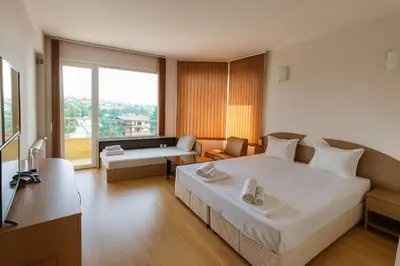 a bedroom with a large bed and a living room at Hotel Avis in Sandanski