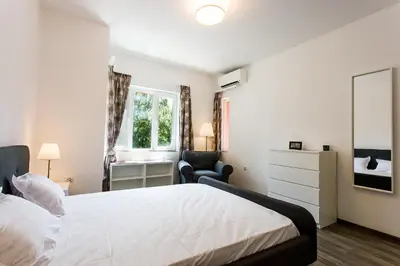 a bedroom with a bed and a chair and a window at Top center big family apartment with garden view in Plovdiv