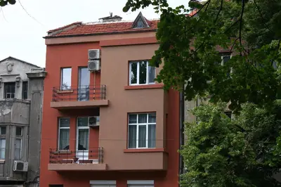 a red building with balconies on the side of it at Top center big family apartment with garden view in Plovdiv