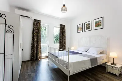 a white bedroom with a bed and a window at Top center big family apartment with garden view in Plovdiv
