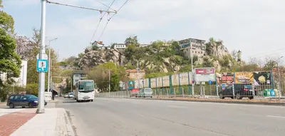 a white bus driving down a street with a hill at Apartments Nasini by Flat Mаnager in Plovdiv