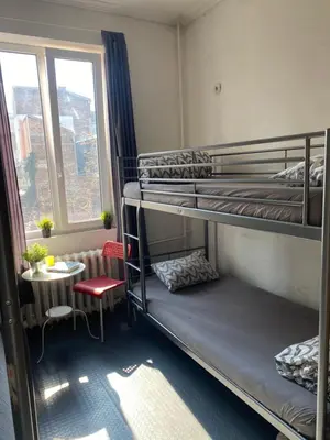 a room with bunk beds and a table and a window at Bla Bla Hostel in Sofia