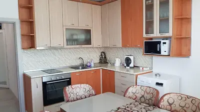 a kitchen with wooden cabinets and a table and chairs at Д и В 2 - D & V 2 Apartment in Sandanski