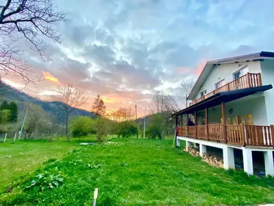 a house with a deck on a green field at Пе́трови Вили in Ribarica