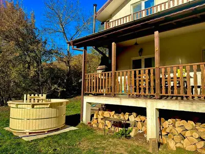 a house with a wooden deck next to a pile of wood at Пе́трови Вили in Ribarica