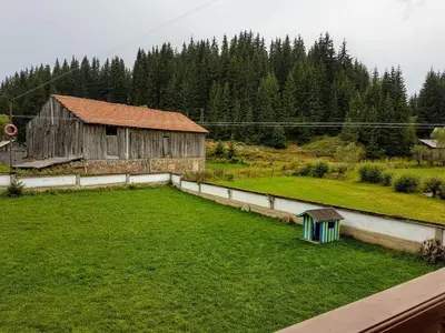 a large green field with a barn and trees at Къща за гости 