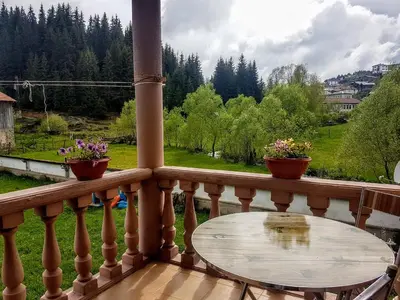 a wooden balcony with a table and flowers on it at Къща за гости 