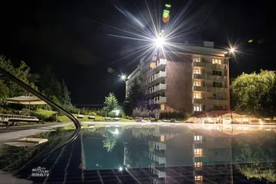 a swimming pool at night with a building in the background at Почивна станция Витоша in Velingrad