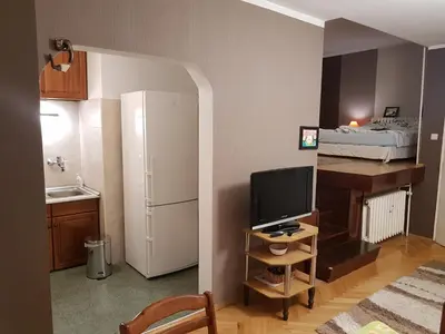 a small room with a kitchen with a television and a bed at Artistic studio in Sofia's top center in Sofia