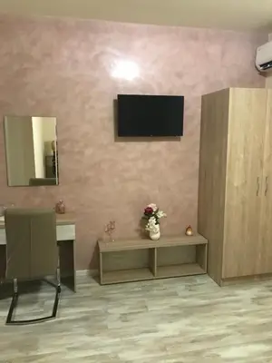 a living room with a table and a television on a wall at ФЛАМА РЕЗИДЕНТС in Plovdiv