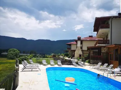 a swimming pool with chairs and a house at Къщи за гости БАШЕВИ in Sarnitsa