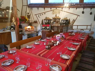 a long red table with plates and glasses on it at Къщи за гости БАШЕВИ in Sarnitsa