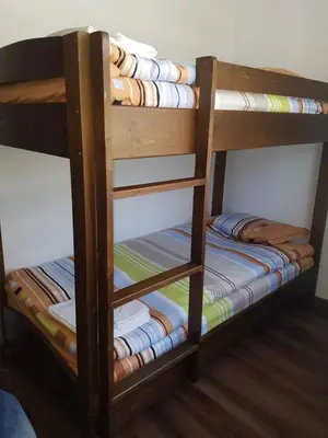 a wooden bunk bed with folded blankets on it at Къщи за гости БАШЕВИ in Sarnitsa