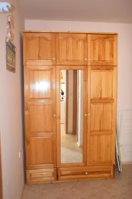 a wooden cabinet with a mirror in a room at Panorama Stoykite Yana apartment in Pamporovo