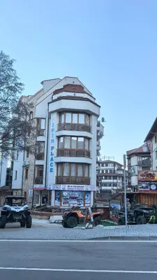 a building with cars parked in front of a street at Cozy Apartment Next to Gondola in Bansko