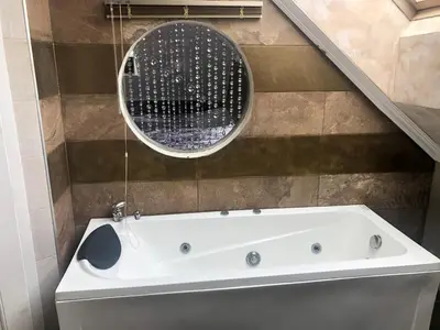 a bathroom with a tub and a round mirror at Стаи за гости Топ Старс Смолян in Smolyan