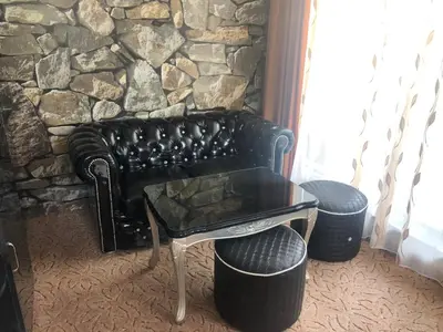 a black leather couch sitting in front of a stone wall at Стаи за гости Топ Старс Смолян in Smolyan