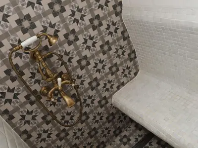 a bathroom with a tiled wall with a brass fixture at Good Stay Sofia Apartments in Sofia