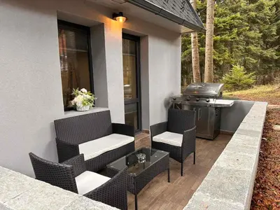 a patio with a grill and chairs and a table at Boro Green Holiday Village in Borovets