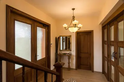 a hallway with a wooden door and a chandelier at Luxury Chalet & Spa Tia Maria with Private SPA in Bansko