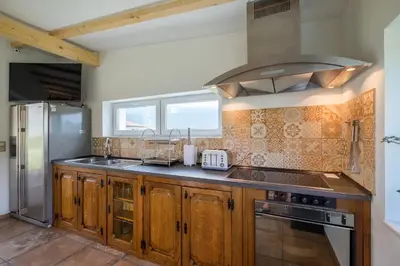 a kitchen with wooden cabinets and a stainless steel refrigerator at Villa ADELHEIDE - Spa, BBQ & Jacuzzi in Beli Iskar