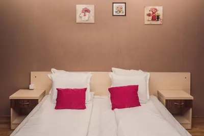 a large white bed with two red pillows on it at Sky Garden House in Velingrad