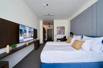 a bedroom with a large white bed and a flat screen tv at Adella Boutique Hotel - Free Secured Parking in Sofia