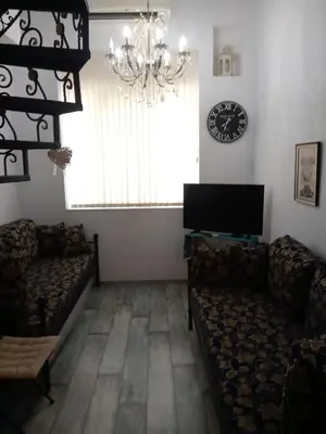 a living room with couches and a television and a chandelier at Cosy House in Sofia