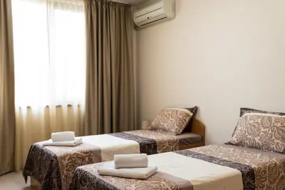 a hotel room with two beds and a chair at Апартамент АВА in Sandanski