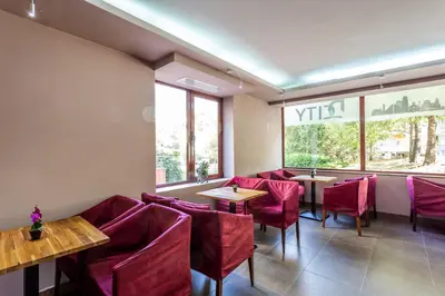 a restaurant with red chairs and tables and a window at CityHome Aparthotel in Sofia
