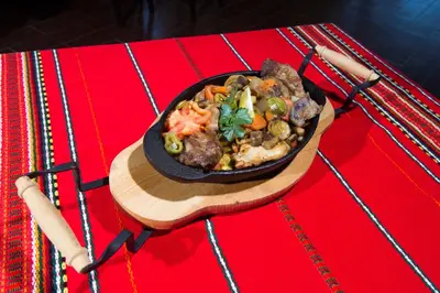 a bowl of food on a wooden plate on a table at Hotel Melnik Хотел Мелник in Melnik