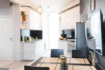 a kitchen with white cabinets and a table and chairs at Vitosha Blvd - 2BR LUX APART in Sofia