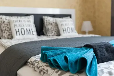a bed with a blue blanket and pillows on it at Vitosha Blvd - 2BR LUX APART in Sofia
