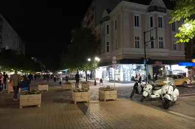 a white scooter parked on a city street at night at Vitosha Blvd - 2BR LUX APART in Sofia