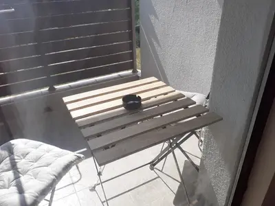 a black cat sitting on a wooden bench on a balcony at Elza Apartment in Pamporovo