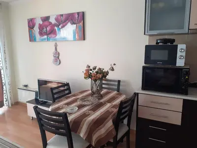 a dining room table with a vase of flowers on it at Elza Apartment in Pamporovo