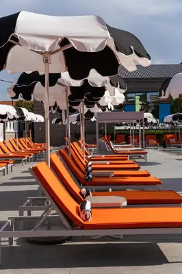 a row of orange lounge chairs with umbrellas at Kamengrad Hotel & SPA in Panagyurishte