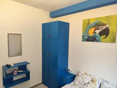 a bedroom with a blue cabinet and a painting of a parrot at Стаи за гости Ве-Бо-Ли** in Bankya