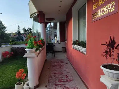 a red building with potted plants on the side of it at Стаи за гости Ве-Бо-Ли** in Bankya