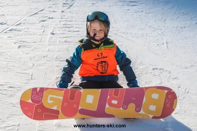 a young child sitting in the snow with a snowboard at Alpine ski chalet Borovets with sauna in Borovets