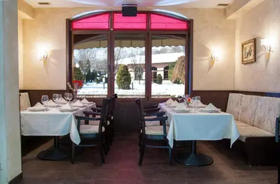 a restaurant with white tables and chairs and a window at Hotel Domaine Peshtera in Peshtera