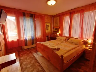 a bedroom with a large wooden bed and windows at Семеен хотел Калина Family hotel Kalina Говедарци in Govedartsi