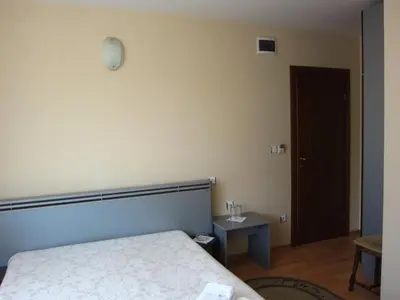 a bedroom with a bed and a table and a door at Family Hotel Bistritsa in Sandanski