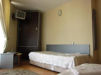 a bedroom with two beds and a tv on the wall at Family Hotel Bistritsa in Sandanski