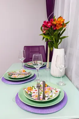 a table with plates and glasses and a vase with flowers at Apartment Valerie walking distance to Top Center in Plovdiv